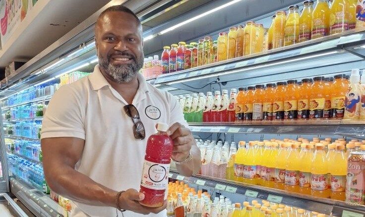 The founder of Juice Fiji holding a bottle of juice in a supermarket